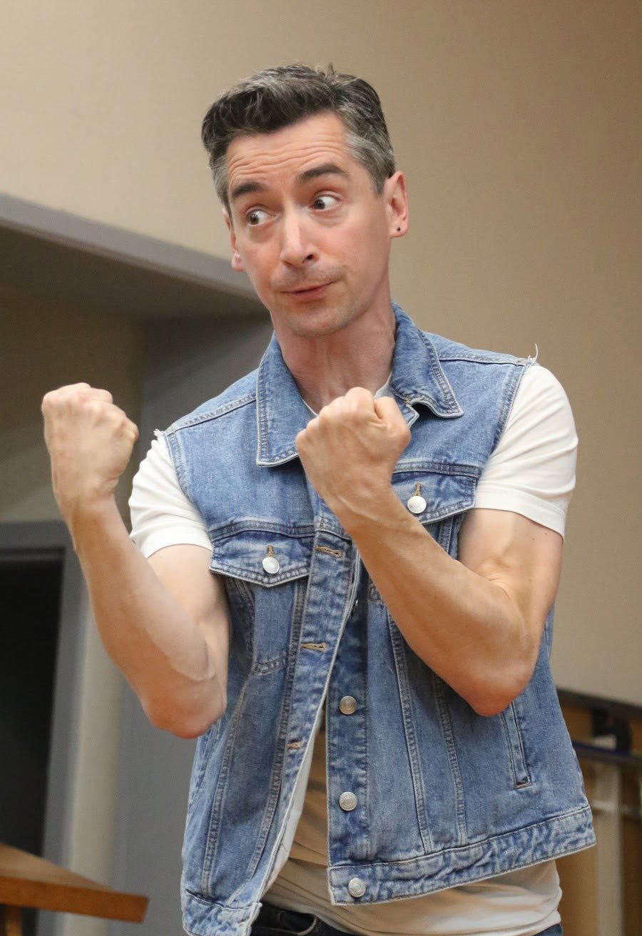 An animated moment in rehearsal with a performer in a denim waistcoat