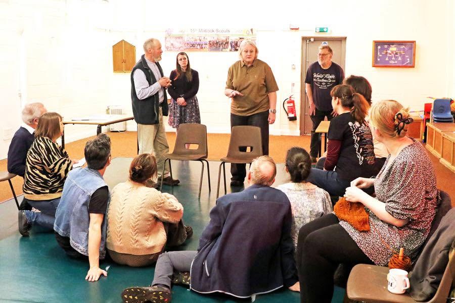The company gathered around a scene in the rehearsal room