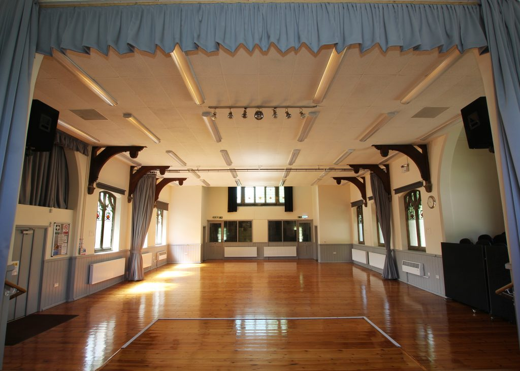 Inside the Imperial Rooms, looking across the wooden-floored hall from the stage, with windows along both sides